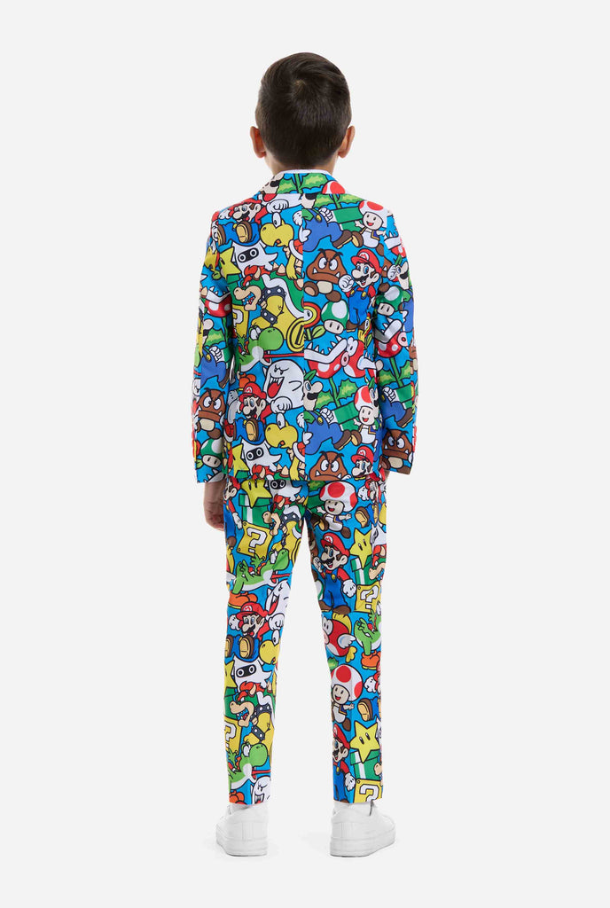 Image of kid wearing a Super Mario all over print suit, consisting of blazer, pants and tie. Main color is blue, but there is also yellow, red and white.