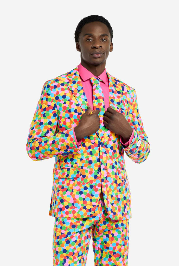 Image of a man wearing an OppoSuits Confetteroni men's suit with confetti print and pink men's shirt. Suit consist of pants, jacket and tie.