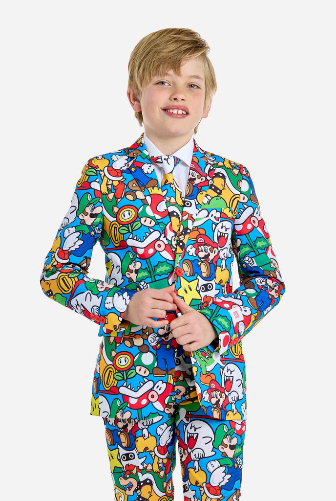 Image of teen wearing a Super Mario all over print shirt, consisting of blazer, pants and tie. Main color is blue, but there is also yellow, red and white.