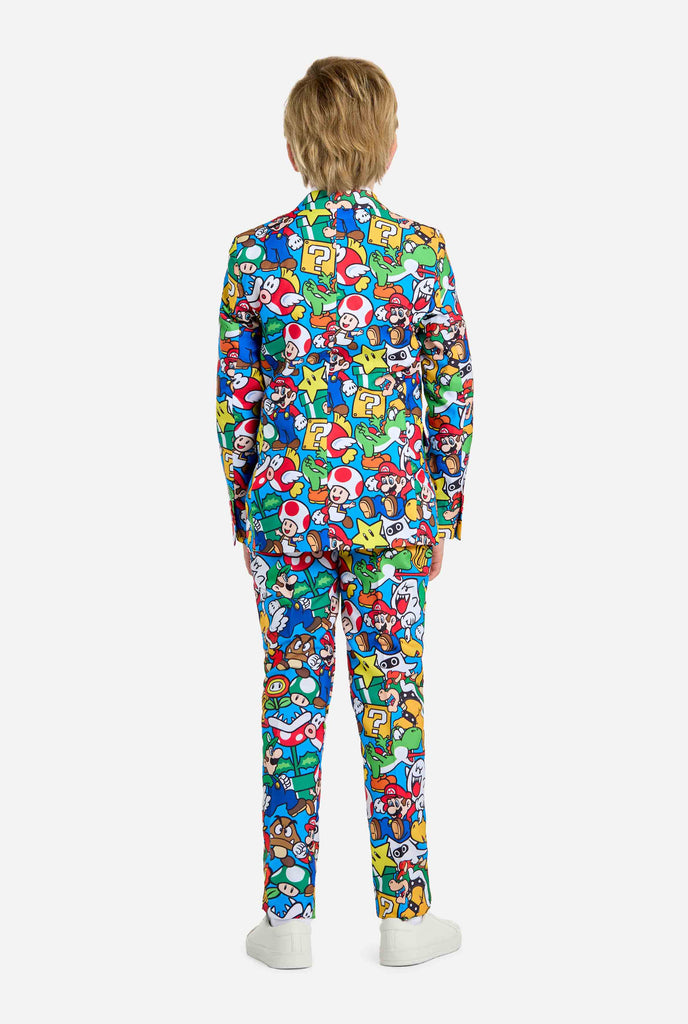 Image of teen wearing a Super Mario all over print shirt, consisting of blazer, pants and tie. Main color is blue, but there is also yellow, red and white.