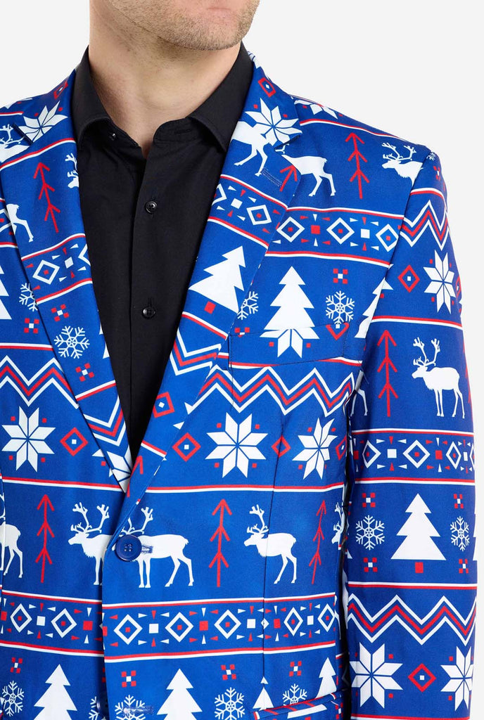 Man wearing blue Christmas blazer for men with Nordic Christmas figures. Man also wearing a black pants and black men's shirt. Chest close up.