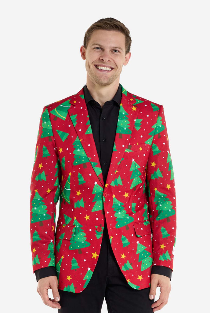 Man wearing red Christmas blazer for men with Christmas trees and stars print. Man also wearing a black pants and black men's shirt.