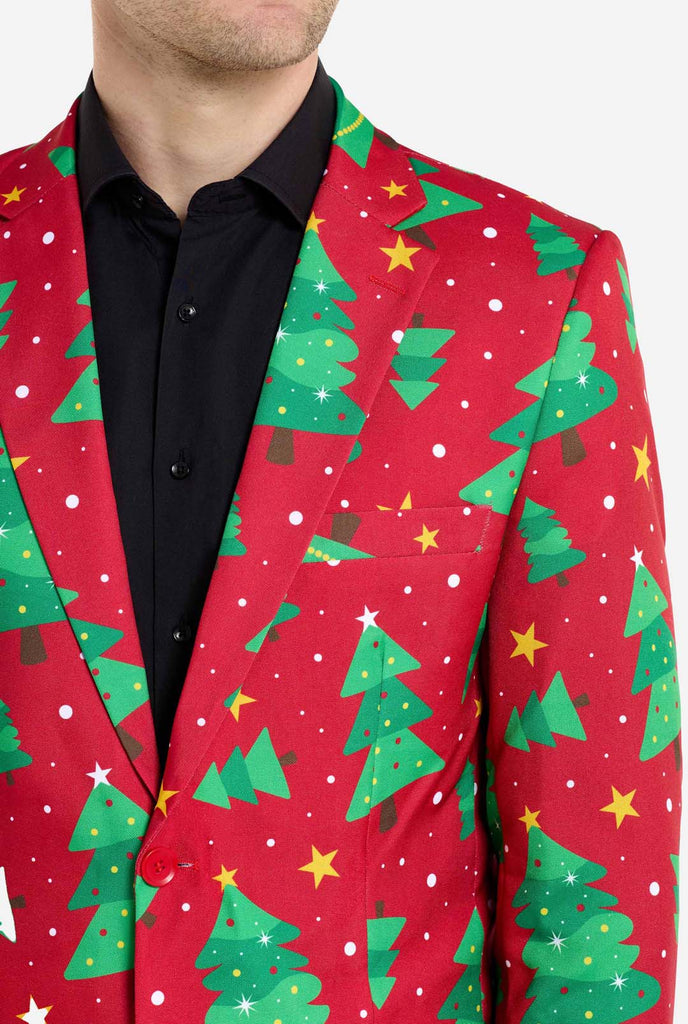 Man wearing red Christmas blazer for men with Christmas trees and stars print. Man also wearing a black pants and black men's shirt. Chest close up.