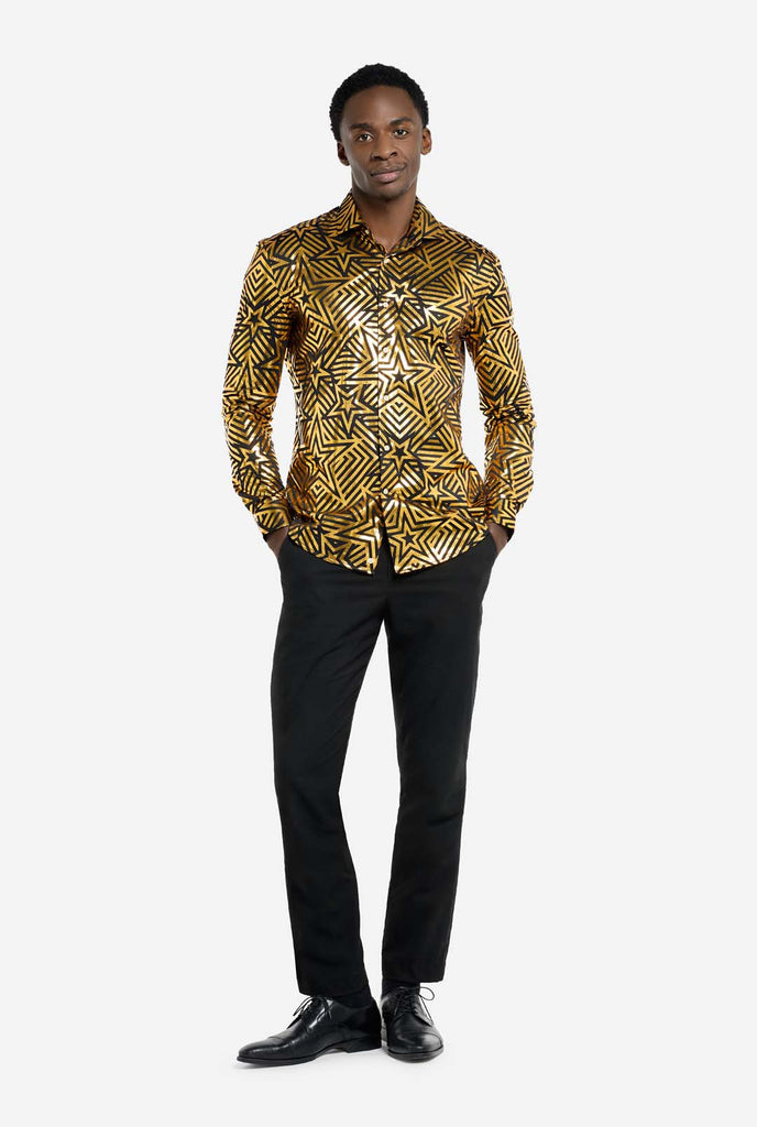 This image features a men’s shirt from OppoSuits with a vibrant gold and black geometric star print pattern. The shirt has a reflective finish that highlights the intricate star and line designs, creating a dynamic and stylish look. Perfect for those who want to stand out, this shirt is both bold and fashionable, ideal for parties, holiday celebrations, or nightlife. The model wears it paired with black pants. Full body image.