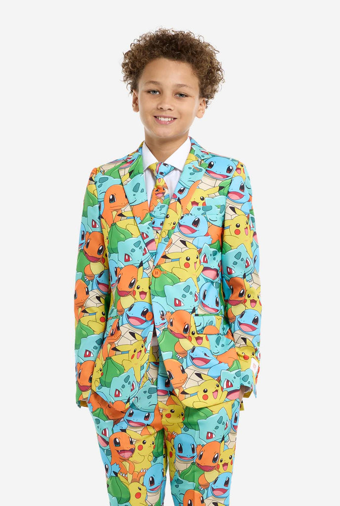 Teen wearing formal multi color suit with all-over Pokemon print. The suit contains the characters Pikachu, Bulbasaur, Charmander and Squirtle.