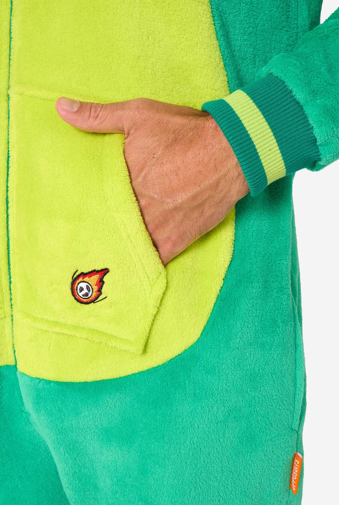 A man is wearing a green dinosaur adult onesie featuring playful hood details and cozy, soft material, perfect for lounging or costume events. Close-up of the kangeroo pocket.