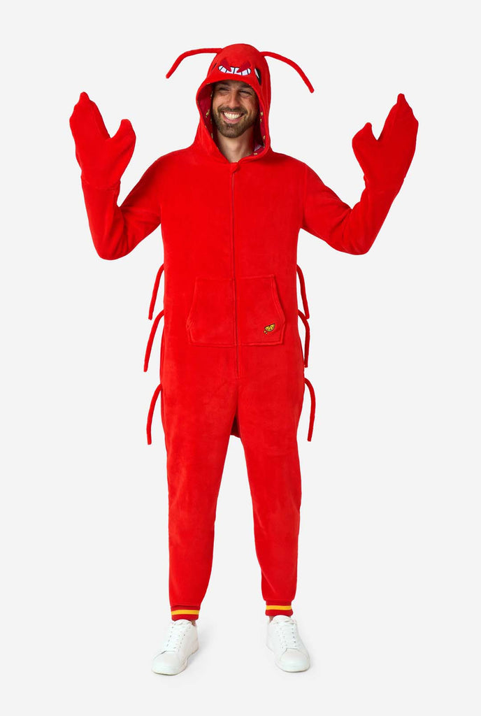 A man is wearing a bright red lobster-themed adult onesie featuring playful hood details and cozy, soft material, perfect for lounging or costume events. including stitched gloves as claws. Man is wearing the gloves and is smiling.