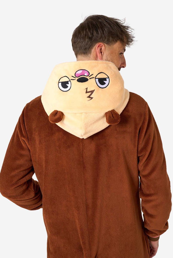 A smiling man is wearing a brown adult onesie designed as an otter. The onesie features a hood with ears, a cute face, and playful otter details, perfect for cozy lounging or costume parties. Upper body close up, view from the back.