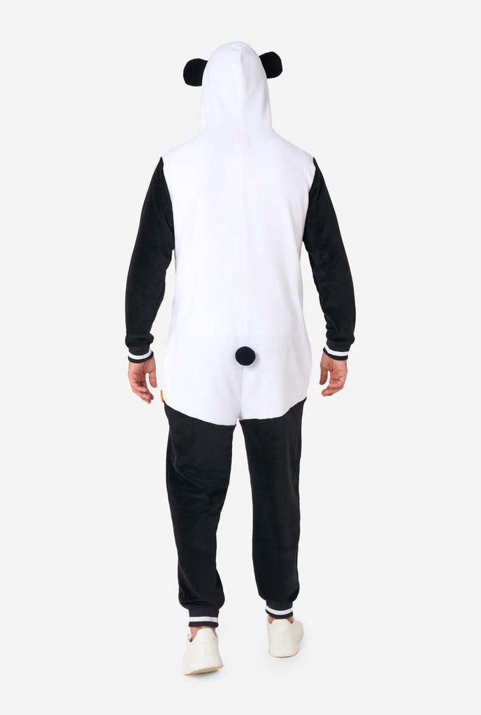 A man is wearing a panda-themed adult onesie. This cozy onesie features black and white panda colors with a playful hood showcasing panda ears and a cute face. Perfect for lounging or fun costume occasions. View from the back.