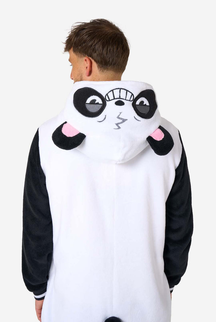 A smiling man wearing a panda-themed adult onesie. This cozy onesie features black and white panda colors with a playful hood showcasing panda ears and a cute face. Perfect for lounging or fun costume occasions. View from the back and hood on down on his back.