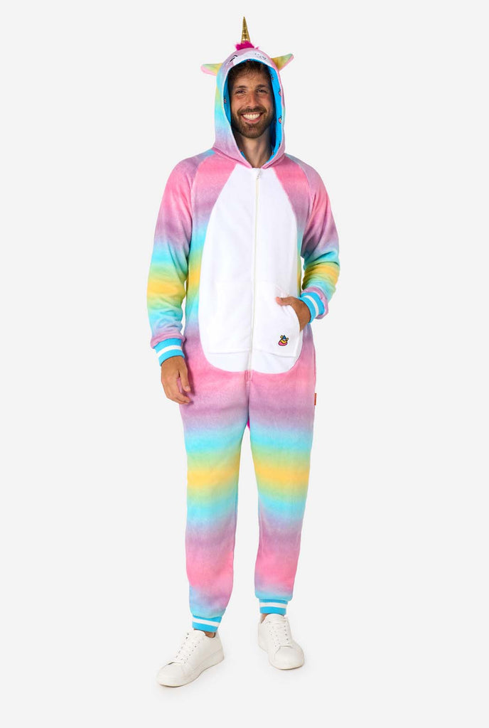 A cheerful man wearing a colorful adult onesie designed as a rainbow unicorn. The onesie features a vibrant gradient of pastel colors, a golden horn, and playful unicorn details, perfect for cozy lounging or costume parties. Full body image.