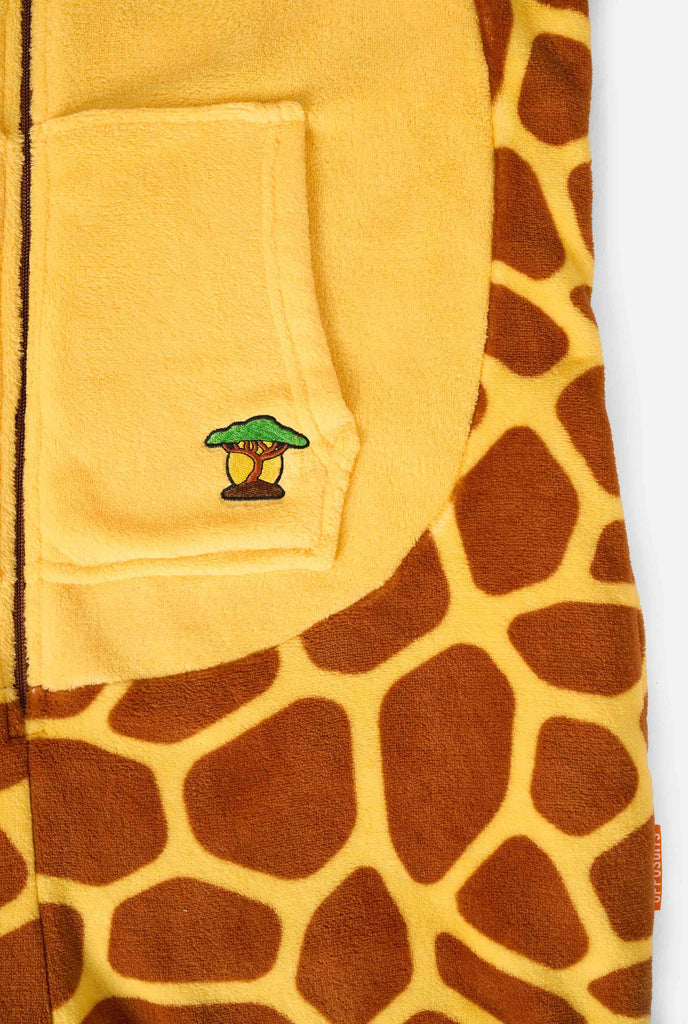 A smiling kid is wearing a brown and yellow kids onesie designed as a giraffe. The onesie features a hood resembling a Giraffes head. Close up.