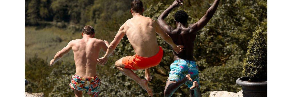 3 man wearing swim shorts jumping in pool 